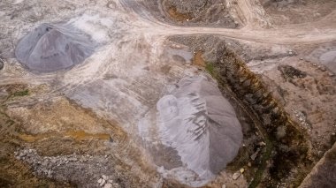 Açık maden ocağında büyük çakıl ve taş yığınları var. Etrafta kayalar ve taşlar vardı..