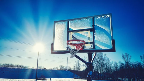 雪が雪の上に輝く太陽の下で風景を覆うバスケットボールの輪 — ストック写真