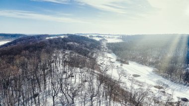 Tepeleri kaplayan karla kaplı parlak bir güneş manzaranın üzerindedir.