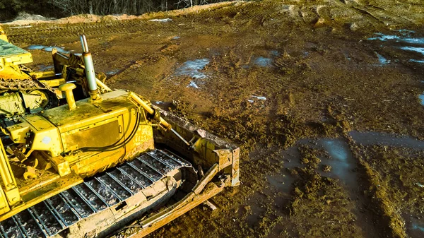挖掘机正在外面清理冬天的泥土 地面上结了冰和雪 春天快到了 雪开始融化 地面被水浸透了 — 图库照片