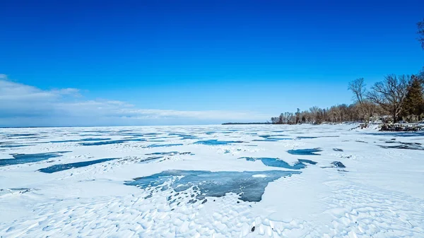 湖は澄んだ空と海岸線に沿って雪で散乱しています — ストック写真