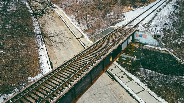 錆びた古い鉄道橋が田舎道を通って伸びている — ストック写真