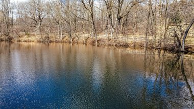 Ağaçlar hala çıplak. Su artık donmuş değil. Ve gökyüzü su yüzeyine yansıyor..