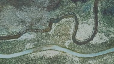 Kar eridi ve bahar geldi. Kırsal bir alanda, yanında patika olan sarmal bir akarsu manzarası..