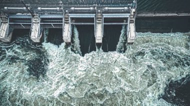 Az miktarda rengi olan siyah beyaz bir araba geliyor. İlkbaharda Fox Nehri üzerindeki açık baraj manzarası