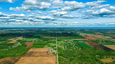 Şehirleri ve çiftlikleri olan kırsal alanların üzerindeki uzak bir gölün bahar manzarası.
