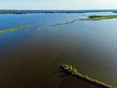 Summertime view of a boat passing the edge of a breakwall path on the Fox River near Oshkosh Wisconsin