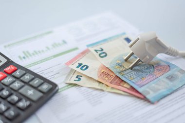 Beyaz bir elektrik kepi, euro banknotları ve elektrik faturasında hesap makinesi. İkametgah müşterileri ve iş kullanıcıları için artan elektrik maliyeti. Elektrik faturaları. Elektrik fiyatları kavramını artırıyor.