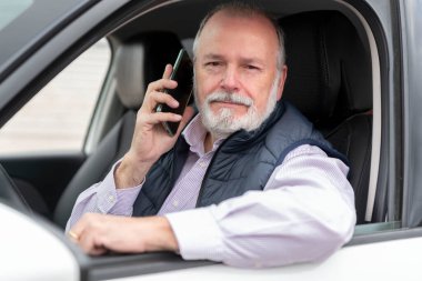 Arabada ya da takside cep telefonu olan yaşlı bir sürücünün portresi