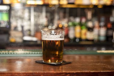 Bardaki ahşap bir masada yarım litre kehribar birasına yaklaş.