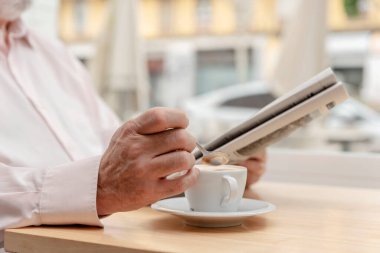 Tanımlanamayan yaşlı bir adamın elinde kahve fincanı tutarken.