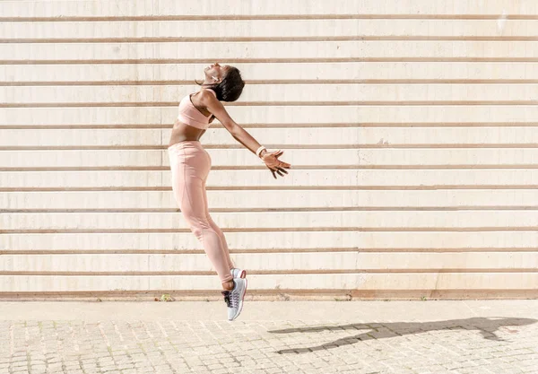 Vältränad Afroamerikansk Kvinna Som Hoppar Solen Med Armarna Utsträckta Tillbaka — Stockfoto