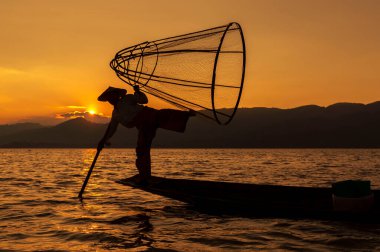 Myanmar 'da günbatımında Inle Gölü' nde geleneksel bir Burmalı balıkçının silueti..