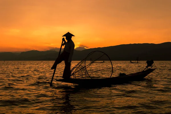 Myanmar 'da günbatımında Inle Gölü' nde geleneksel bir Burmalı balıkçının silueti..