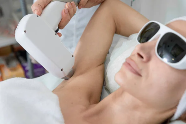woman during underarm laser hair removal treatment in the beauty salon