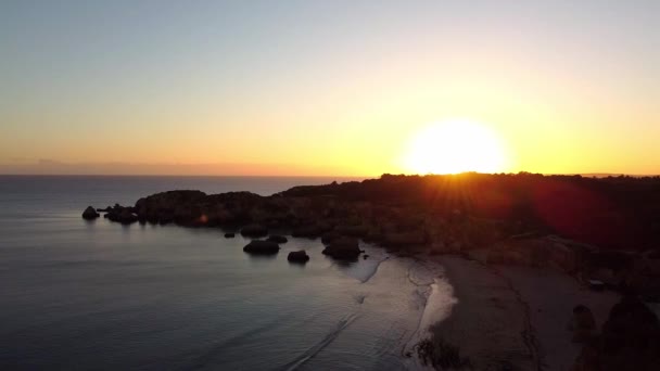 Сонячне небо з повітряним дроном. Сонце зайшло через гірський силует. Пустельний пляж. — стокове відео