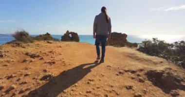 Uçurumun kenarında yürüyen bir erkek. Uçuruma ve altın plaja bakıyorum..