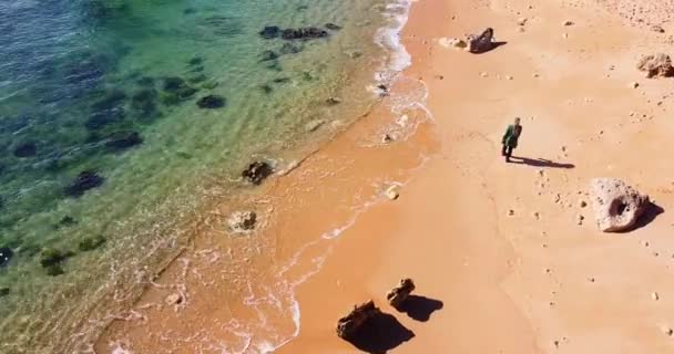 Luchtfoto van een eenzame vrouw die over het gouden strand loopt. Prachtige golven. — Stockvideo