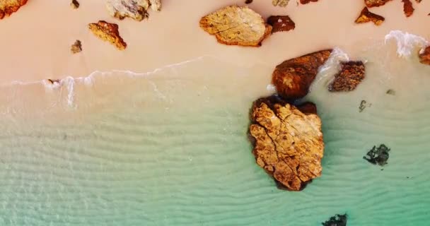 Video von oben nach unten von einem leeren tropischen Strand mit weißem goldenem Sand. Draufsicht leerer und felsiger sauberer Strand. Berühmtes Touristenziel, keine Menschen. Wellen kommen langsam in den Sand. Kristallklares Wasser — Stockvideo