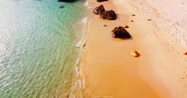 Volledig leeg paradijselijke zeestrand. Kristalhelder blauw water beweegt langzaam. Idyllische tropische zee strand, gouden zonsondergang met rotsen. Geen mensen. Gouden zonsondergang en zand. Hete middag op een leeg strand — Stockvideo