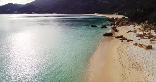 Drone shot of a tropical island beach with mountains on the background. Golden sunset, white sand with rocky coastline. No people on the beach, relaxing and paradise. Tropical, mountain silhouette, — Stock Video