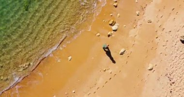 Tropikal plajda tek başına yürüyen güzel sarışın bir kadının videosu. Sıcak yaz günü, berrak su, altın plaj. Seyahat kavramı, hayatta mutluluk, seyahat tatil yaşam tarzı.