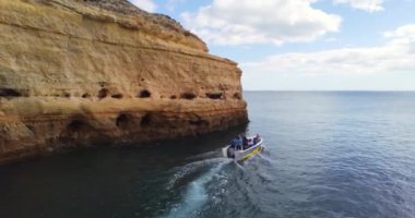 Limandan bir tekne ayrılıyor. Teknede bir sürü insan var. Sarı kireçtaşı duvarlar. Delikli kayalık kayalıklar. Tekneyle gidiyorum. Okyanusa gitmek, hiç bitmeyen okyanusa. 