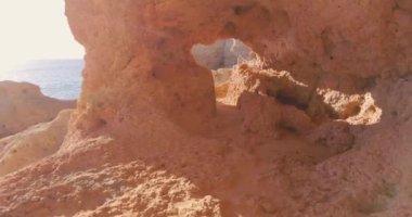 Kireçtaşı deliğinden geçiyor. Portekiz sahilindeki mağarada yürüyorum. Ünlü turist mekanı. Mağaradan güzel bir okyanus manzarasına bakıyorum. Sarı ve turuncu kireç taşı, kayalar ve kayalıklar