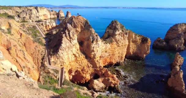 Overlooking magnificent limestone coast and stairs going down the beach with blue turquoise ocean. Yellow and orange rocks cliffs in the ocean. Famous destination. Background texture, wall inspiration — Stock Video