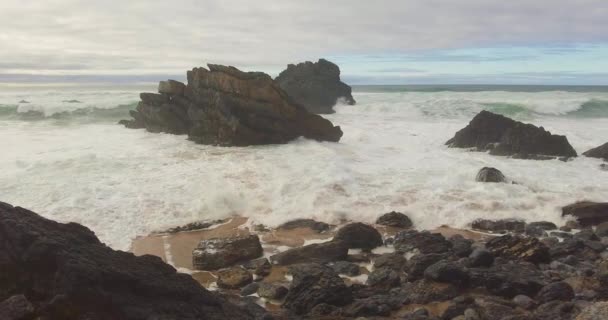 Habzó hullámok törik át a sziklás partvonalat. Kék türkiz hullám víz textúra. — Stock videók
