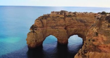 Arco Natural. Portekiz, Algarve sahilinde doğal bir kemer. Algar de benagil. Turistik bir öğleden sonra manzarası, dramatik bir manzara. Okyanusun üzerinde taş kemer insanlar yürüyor. 
