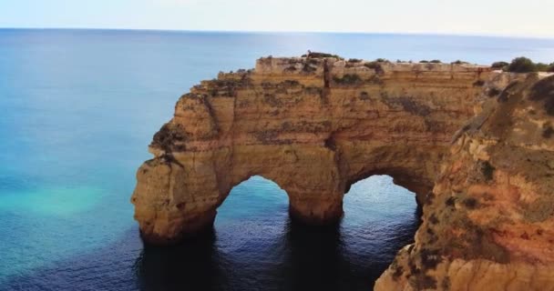 Arco Natural. Arco natural na costa algarvia, Portugal. Algar de benagil. Vista panorâmica da tarde do destino turístico, paisagem dramática. Arco de pedra acima do oceano.. Pessoas andando — Vídeo de Stock