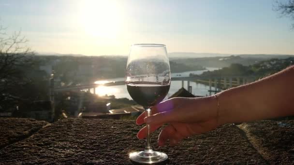 Primo piano di una mano che prende un bicchiere di vino su uno sfondo bellissimo paesaggio urbano tramonto. — Video Stock