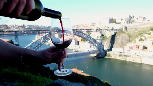 Αγνώριστο χέρι ρίχνει στον εαυτό του ένα κόκκινο κρασί, Douro ποτάμι στο παρασκήνιο — Αρχείο Βίντεο