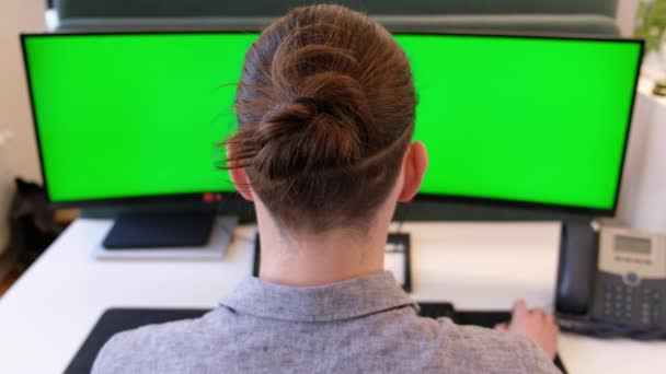 Zakenman met groen scherm op een laptop en telefoon opnemen. Kijk van achteren. Een jonge Europeaan die op afstand werkt en de telefoon opneemt. Groene scherm computer en onherkenbare man. — Stockvideo