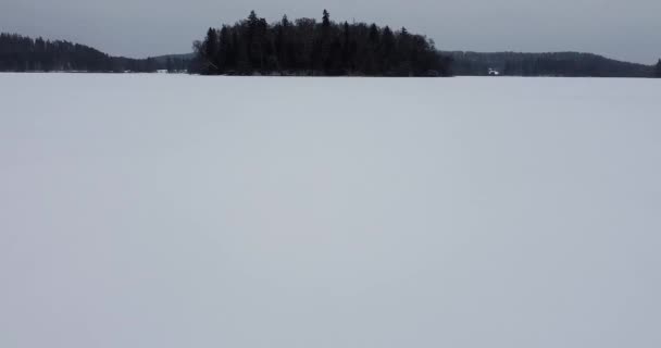 氷結した湖を飛び越えて 氷結した湖の中の小さな島を行き来しています 島と凍結湖 雪に覆われた木 黄昏時 ムーディー暗い天気 冬の季節 ドローン映像 — ストック動画