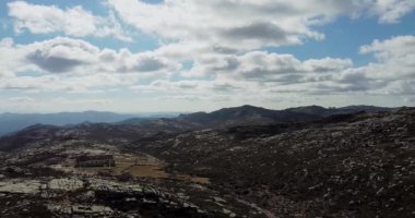 Minas dos Carris arka planda. Dağlarda terk edilmiş bir köy. Kaya oluşumunun üzerinde uçuyorlar. Yeşillik ormanı ve arkadaki mavi dağlar. Geride bırakılan evler. . 