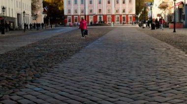 Eski kasaba mimarisinin manzarası, kasaba meydanının önünden geçen insanlar. Merkezde belediye binası var. Açık mavi gökyüzü ve arkada sarı sonbahar ağaçları. - Evet. Yüksek kalite 4k görüntü