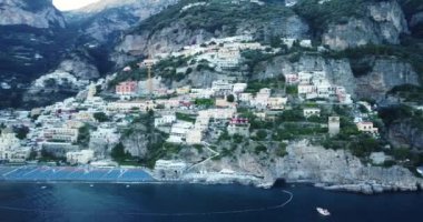 Napoli, İtalya 'daki güzel Positano hava manzarasının üzerinde uçuyor. Amalfi kıyısındaki beyaz kasaba, beyaz sahil manzarası ve hareket eden ve yüzen tekneleri olan mavi okyanus. Şehrin üzerinde uçuyor