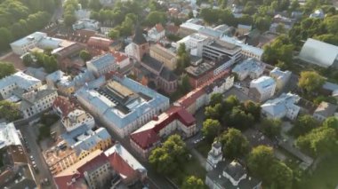 4K hava görüntüleri eski kasabanın üzerinde. Estonya, Tartu. Kilisenin kulesi. Bir meydanın önündeki katedral, kamerayla yukarı doğru eğiliyor. Kırmızı çatılar. Yeşil şehir. Güzel seyahat yeri 