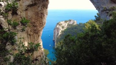 Arco Naturale 'e bakıyorum. Eşsiz kaya oluşumu. Zaman ayarlı hiperhız. Tekneler ve yatlar suda hareket ediyor. Seyahat güzergahı, Capri Adası, İtalya. Mavi su. Doğal kireçtaşı kemeri.