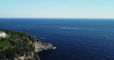 Akdeniz 'de hızla hareket eden yat ve teknelerin güzel hava manzarası. Dağ kıyısında İHA uçuşu. Yelkenli. Turkuaz su. Kayalık kayalıklar, mavi su, yüzen kayıklar, yeşillik.