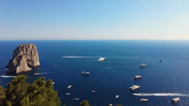 İtalya, Capri Adası 'ndaki Akdeniz' de demirleyen ve ata binen yat ve teknelerin güzel hava manzarası. Denizde kaya oluşumu. Gemiler okyanusta hızlı hareket ediyor. Turkuaz suyu temizle