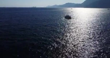 Uzaklaşırken teknenin etrafında uçmak. Akdeniz 'de çok sayıda tekne ve arka planda dağlar var. Mavi göl, tatil yeri. İtalya kıyı şeridi. Nakliye gemisi. 