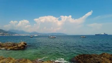 Sahilde oturuyor ve soldan sağa bakıyor. Kristal berrak mavi Akdeniz. Yatlar ve tekneler demir atıyor. Tatil yeri. Güneşin tadını çıkarıyorum. İtalya, Amalfi Sahili. 