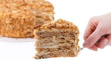 Napolyon keki, elinde spatuladan kesilmiş bir dilim, beyaz arka planda yakın plan izole edilmiş.