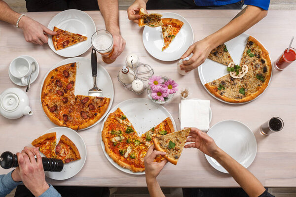 Friends eat pizza together. Group of people at the table eating Italian food. Top view flat lay.