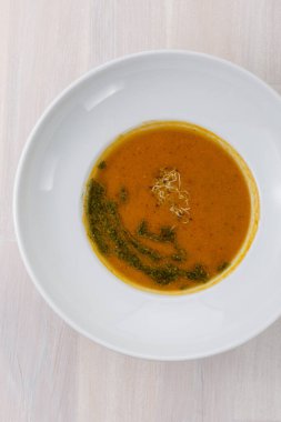 carrot soup with micro greens and green oil on the table top view flat lay