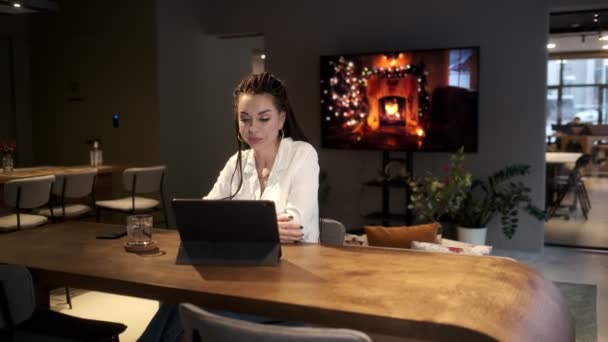 레게 머리를 가진 한 아름다운 소녀는 탁자에 탁자에 앉아 타블렛을 들고 가족들 과 비디오 링크를 통해 의사소통을 한다. 의사소통 개념. — 비디오