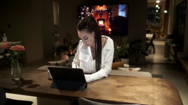 Dziewczyna w dredach w białej koszuli, korzystająca z tabletu cyfrowego na lekcji online, wyciąga wnioski z wideo za pomocą tabletu. Koncepcja uczenia się online. — Wideo stockowe